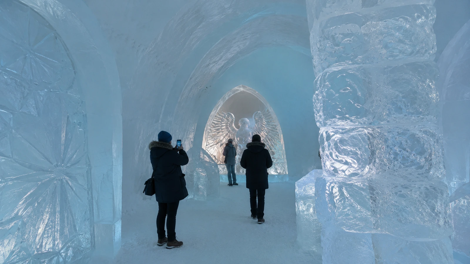 Visitors exploring ICEHOTEL ice rooms and ice art during a daytime visit